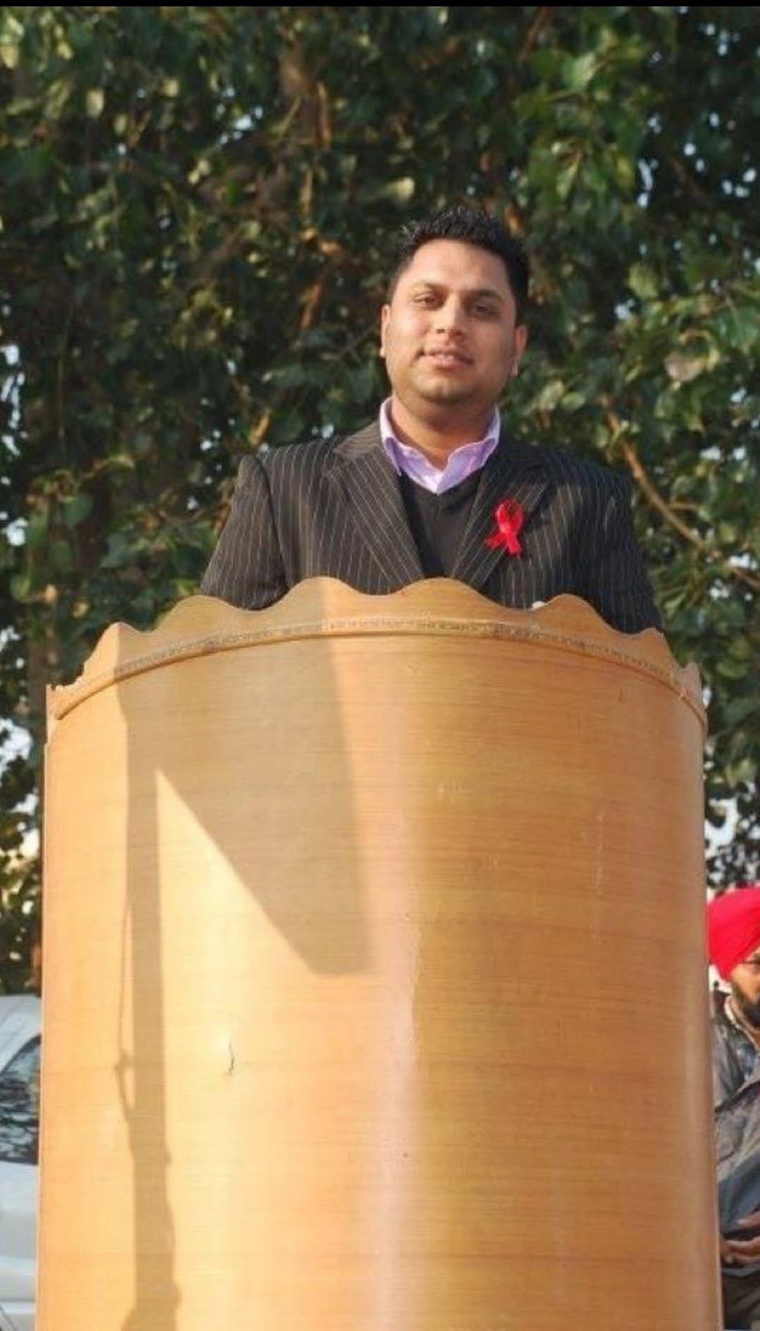 Young Varinder Singh speaking from a podium during an early community service gathering in Punjab