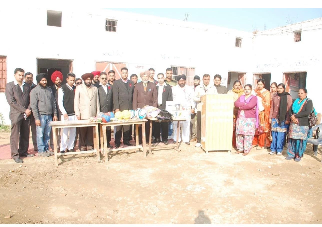 Community members gathered with donated books and sports equipment at a school in Punjab